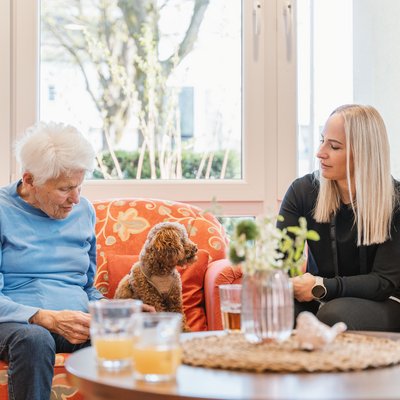 Mitarbeiterin mit Hund und Gast auf Couch